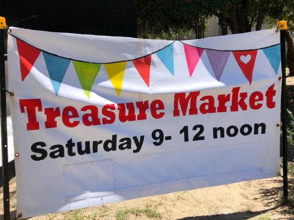 A sign in front of the church that reads 'Treasure Market Saturday 9 - 12 noon'.